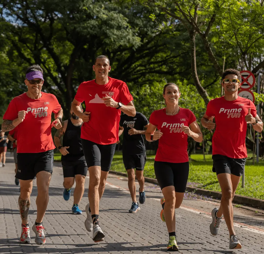 Alunos da Prime Run correndo juntos no parque, com a camiseta vermelha da assessoria
